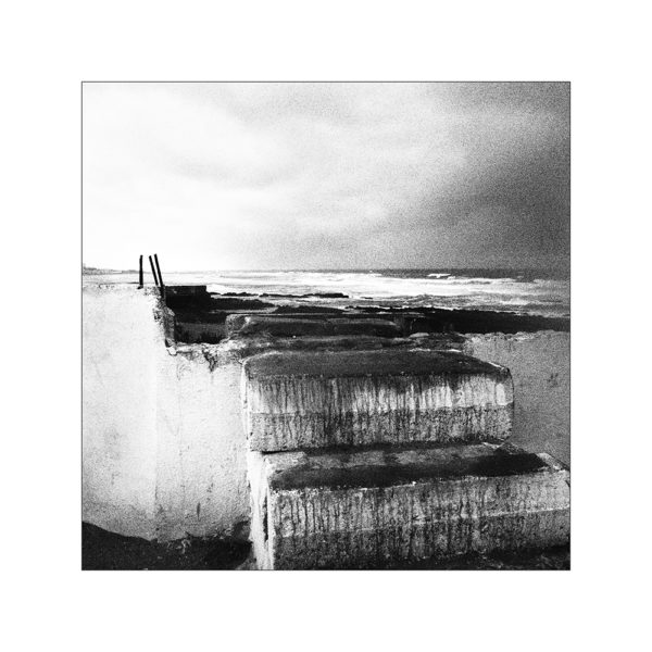 Makeshift stairs lead to an abandoned construction site and to the sea under a rainy sky. Casablanca, Morocco. Des escaliers de fortune menent a un chantier abandonne et a la mer sous un ciel de pluie. Casablanca, Maroc.